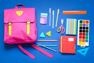 Composition with stylish school backpack and different stationery on blue background clipart