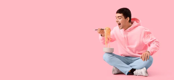 Młody Człowiek Jedzący Chiński Makaron Różowym Tle Miejscem Tekst — Zdjęcie stockowe
