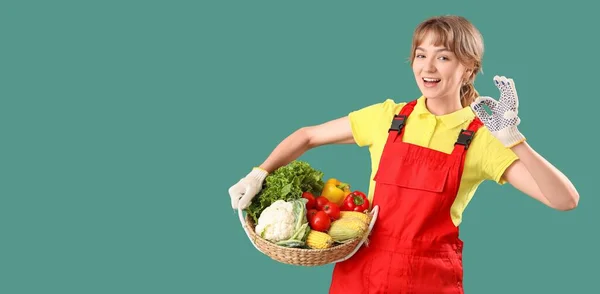 快乐的年轻女农民 提着柳条篮 满满一篮子不同的蔬菜 在绿色的背景上摆出一副不错的姿势 上面有文字的空间 — 图库照片
