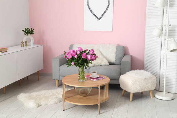 Vase of pink peonies on coffee table with couch in living room