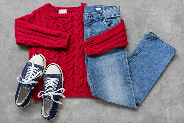 Knitted children's sweater, jeans and shoes on grunge background