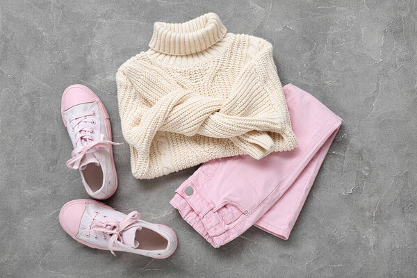 Стильный детский свитер, брюки и резиновые туфли на фоне гранжа