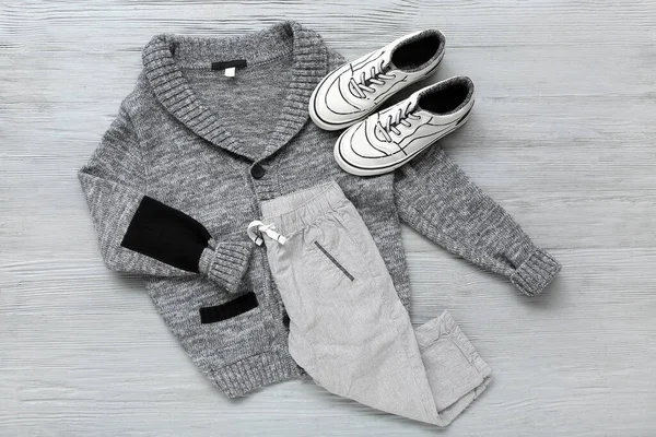 灰色木制背景的时髦儿童毛衣 裤子和鞋子 — 图库照片