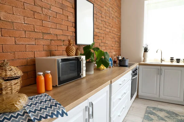 Kitchen counters with microwave oven, utensils and orange juice