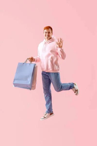 带着粉色背景购物袋的跳跃男子 — 图库照片