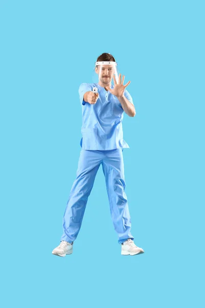 Médico Macho Saltando Con Termómetro Infrarrojo Sobre Fondo Azul —  Fotos de Stock