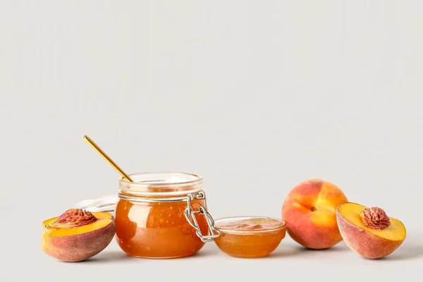 Jar and bowl of sweet peach jam with fresh fruits on white background