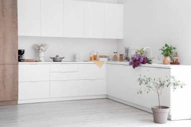 Beyaz tezgahlı ve çiçekli aydınlık mutfağın içi.