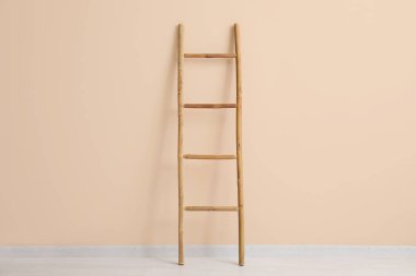 Bej duvarın yanındaki tahta merdiven.