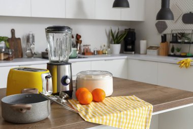 Blender, tost makinesi, meyve sıkacağı, portakal ve mutfak masasındaki ahşap tencere.