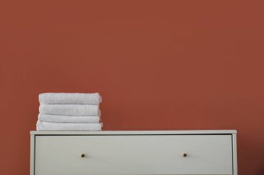 Renk duvarının yanındaki çekmecelerin üzerine temiz havlu yığını, yakın plan.