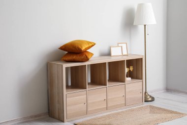 Yastıklı ahşap dolap ve beyaz duvarın yanında boş çerçeveler.