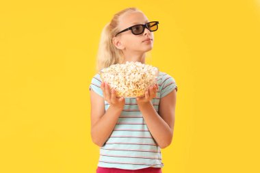 Üç boyutlu sinema gözlüklü, sarı arka planda patlamış mısırlı tatlı kız.