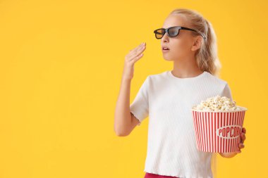 Üç boyutlu sinema gözlüklü, sarı arka planda patlamış mısırlı bir kız.