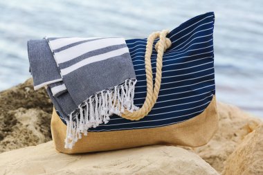 Okyanus kıyısında üzerinde plaj battaniyesi olan bir yaz çantası.