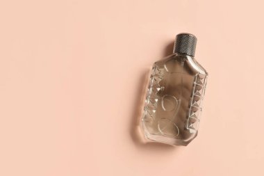 Pembe arka planda bir şişe lüks parfüm.