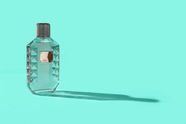 Turkuaz arka planda bir şişe lüks parfüm.