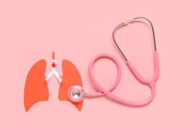 Beyaz kurdeleli kağıt ciğerler ve pembe arka planda steteskop. Akciğer kanseri kavramı
