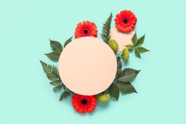 Boş kağıt çarşaflı kompozisyon, yeşil yapraklar ve turkuaz arka planda güzel çiçekler.