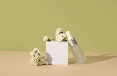Gerekli yağ şişesi, sıva podyum ve renkli arka planda güzel çiçekler içeren kompozisyon