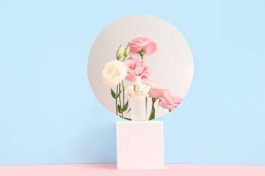 Gerekli yağ şişesi, sıva podyumu ve renk arka planında güzel Eustoma çiçekleri olan kompozisyon