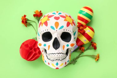 Meksika Ölüler Günü (El Dia de Muertos) için boyanmış insan kafatası ve yeşil arka planda çiçekler