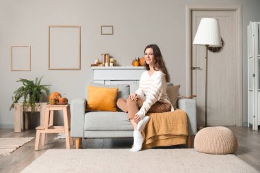 Evdeki kanepede oturan genç bir kadın.