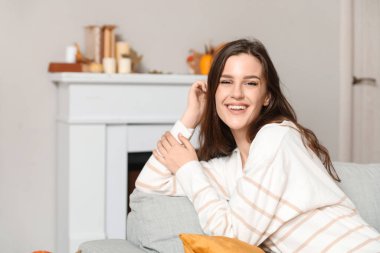 Evdeki kanepede oturan genç bir kadın.