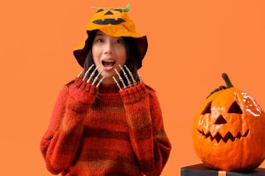 Cadılar Bayramı için giyinmiş, turuncu arka planda balkabağı olan genç Asyalı kadın.