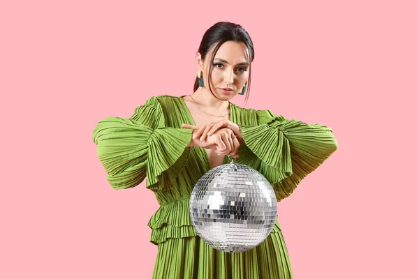 stock image Fashionable beautiful woman in stylish green dress with disco ball posing on pink background