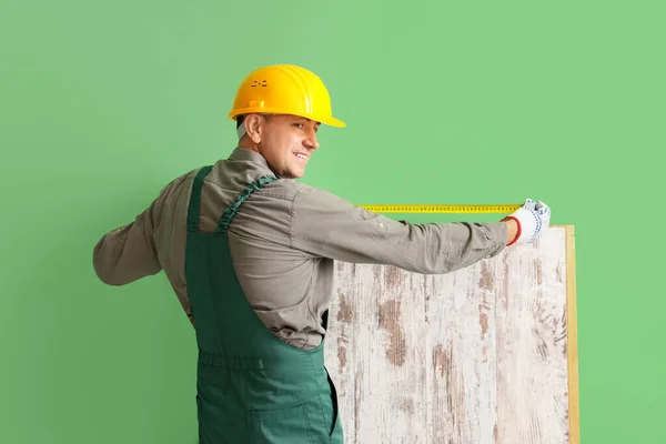 Olgun Inşaatçı Yeşil Duvarın Yanında Ahşap Kalas Ölçüyor — Stok fotoğraf