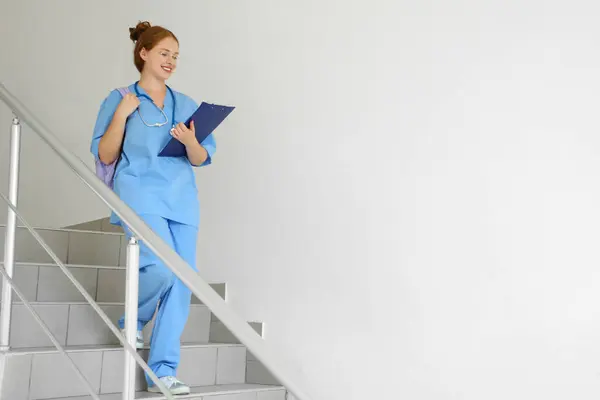 Female medical student with clipboard on stairs at university