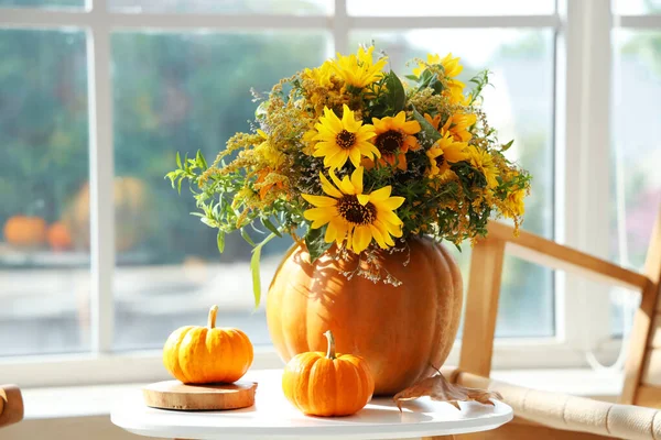 Pumpkins with autumn bouquet on table in living room