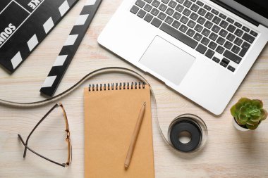 Film, film alkışları ve hafif ahşap arka planda dizüstü bilgisayarlı defter.
