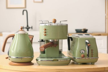 Elektrik ısıtıcısı, tost makinesi ve kahve makinesi mutfaktaki ahşap masada.