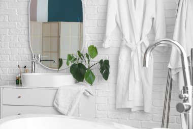 Lavabosu, küveti ve bornozu olan bir banyo.