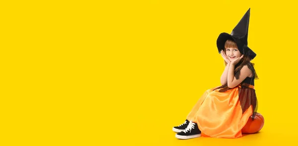 Χαριτωμένο Κοριτσάκι Ντυμένο Μάγισσα Για Halloween Κάθεται Κολοκύθα Κίτρινο Φόντο — Φωτογραφία Αρχείου