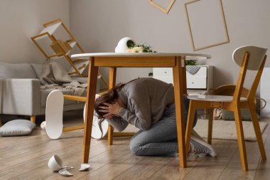 Deprem sırasında yemek masasının altında saklanan genç bir kadın.
