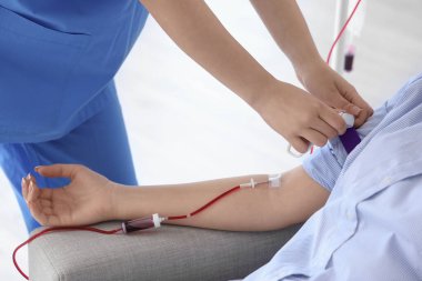 Genç bağışçıyı klinikte kan nakline hazırlayan hemşire, yakın plan.