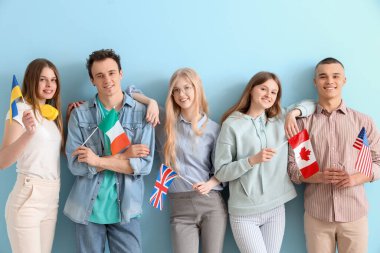 Mavi arka planda farklı ülkelerin bayraklarına sahip bir grup öğrenci