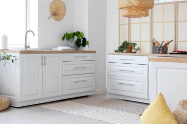 Pencereye yakın beyaz tezgahlı aydınlık mutfağın içi.