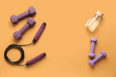 İp atlama, dambıl ve renkli arka planda bir şişe su.