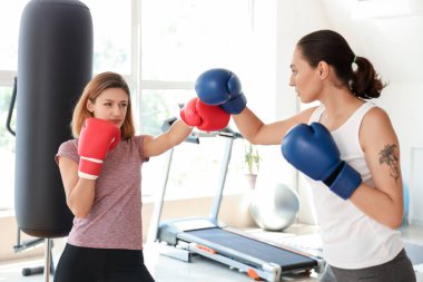 Spor salonunda boks eldivenli genç kadınlar kavga ediyor. Nefsi müdafa kavramı