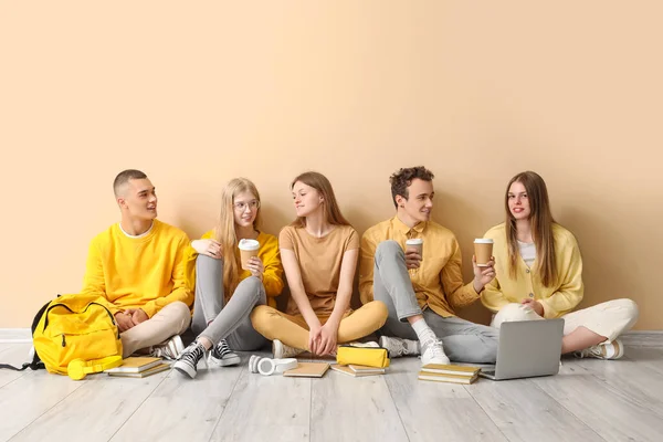 Группа Студентов Сидящих Полу Возле Бледно Желтой Стены Пьющих Кофе — стоковое фото