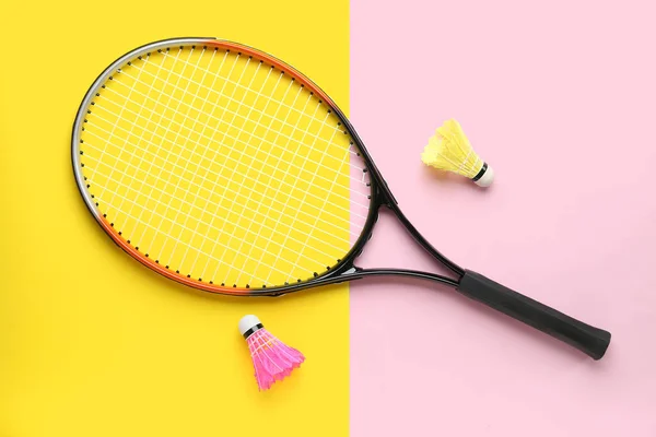 Badminton shuttlecocks and racket on color background