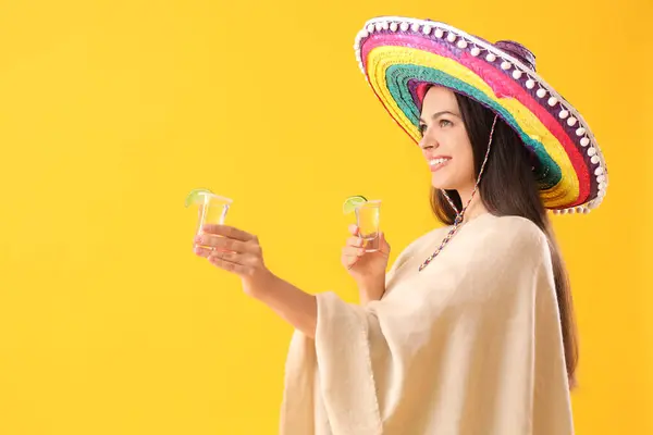 年轻美丽的墨西哥女子 身披长袍 背景是黄色的龙舌兰酒 — 图库照片
