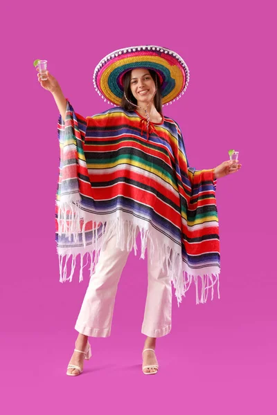 マゼンタの背景にテキーラを持つ美しい若いメキシコの女性 — ストック写真