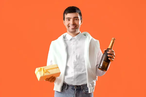 Glücklicher Junger Mann Mit Geburtstagsgeschenk Und Champagner Auf Rotem Hintergrund — Stockfoto