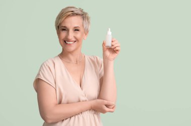 Yeşil arka planda serumu olan olgun bir kadın.