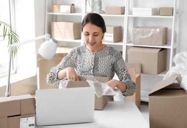 Ofisteki müşteri için paket hazırlayan genç bir kadın.